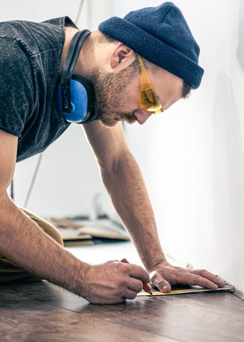 a male worker puts laminate flooring on the floor.